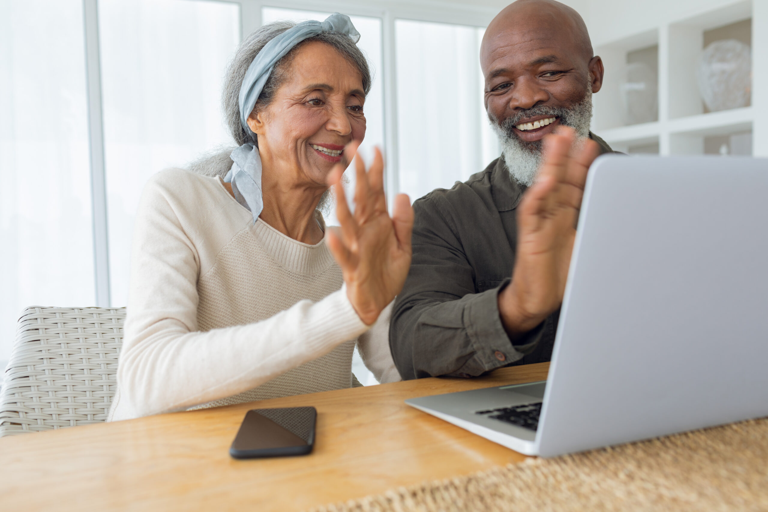 a man and woman waving at a laptop